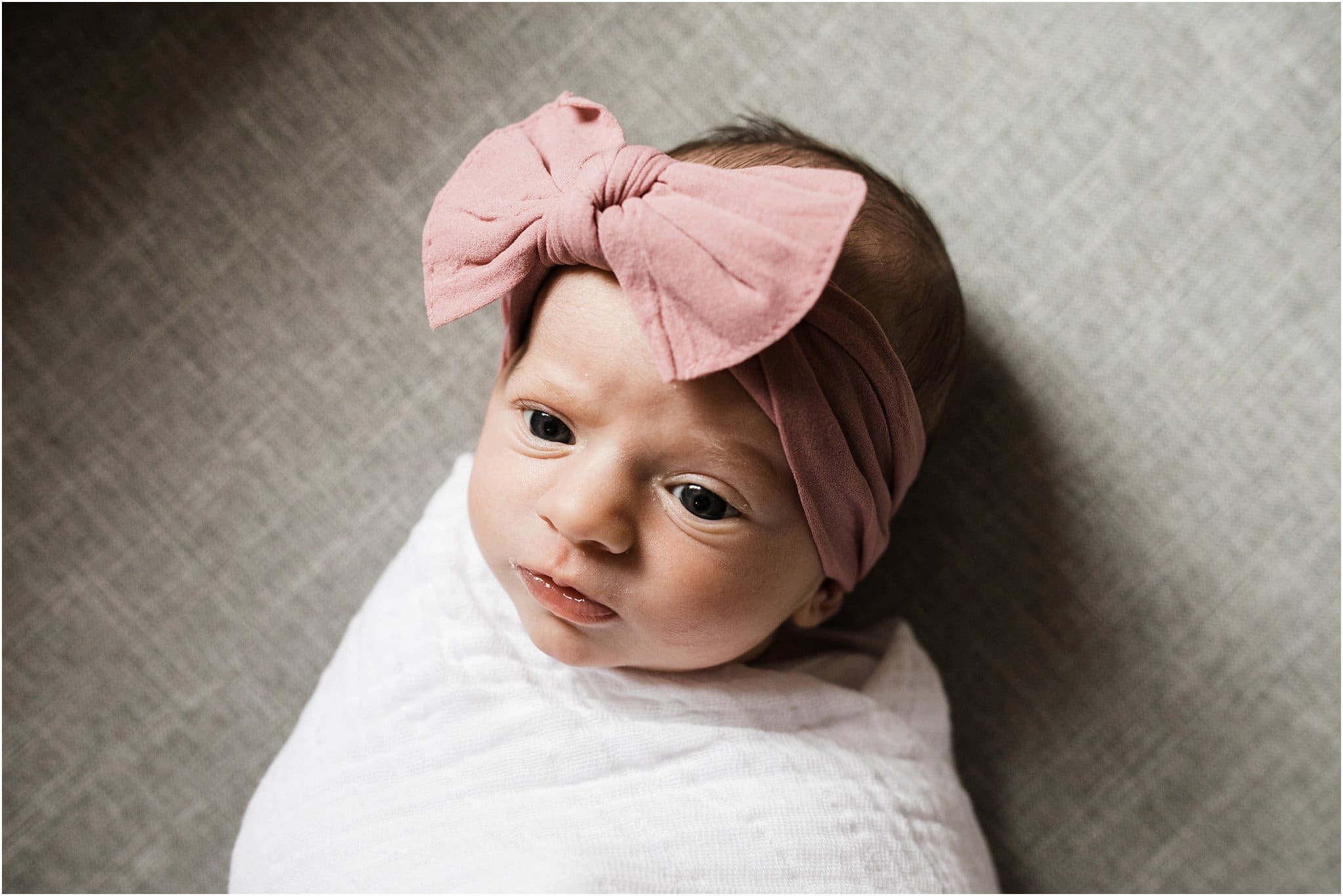 Natural swaddled newborn girl with pink bow