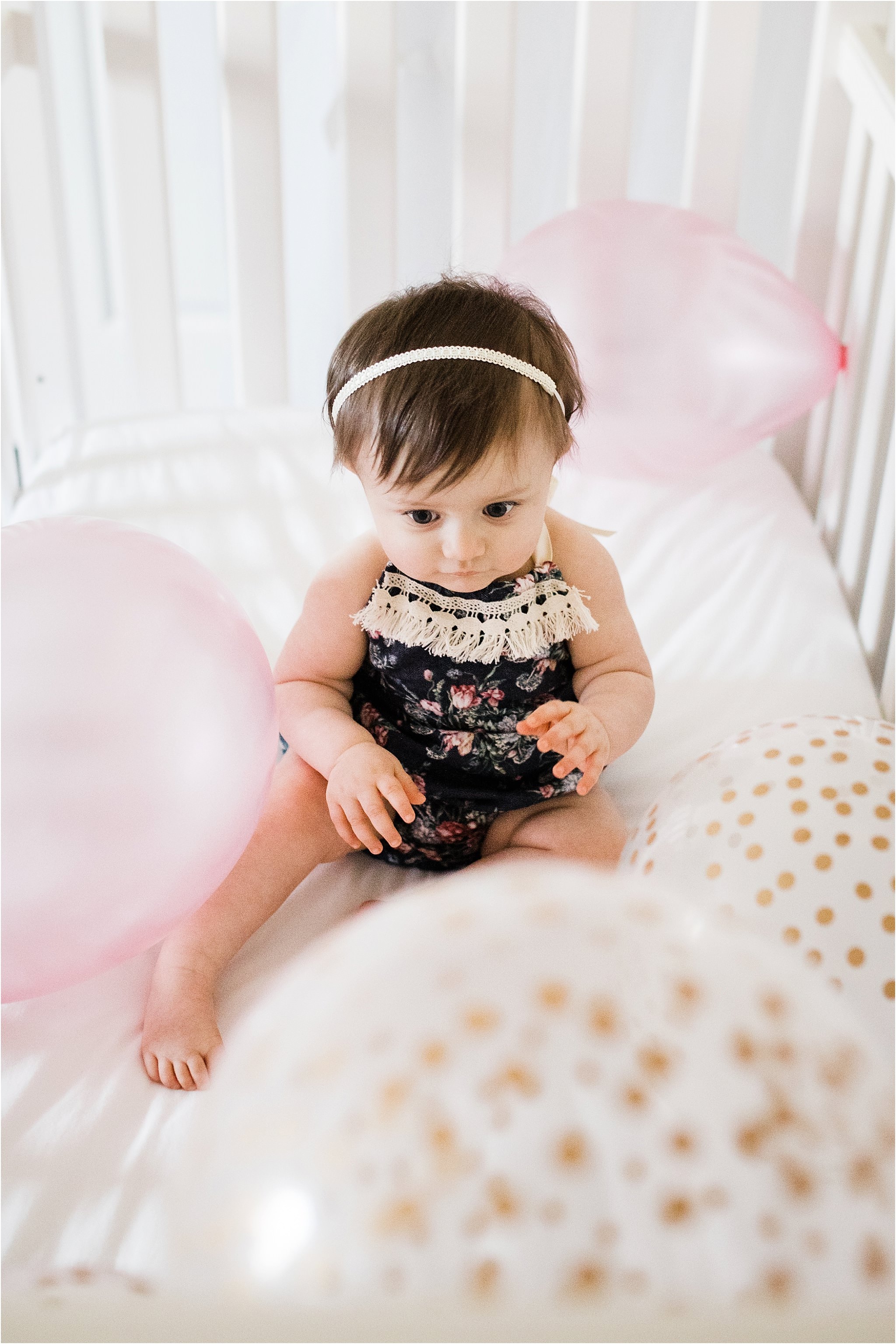 ONE YEAR OLD GIRL IN FLORAL ROMPER PHOTOS IN NURSERY WITH BALLOONS