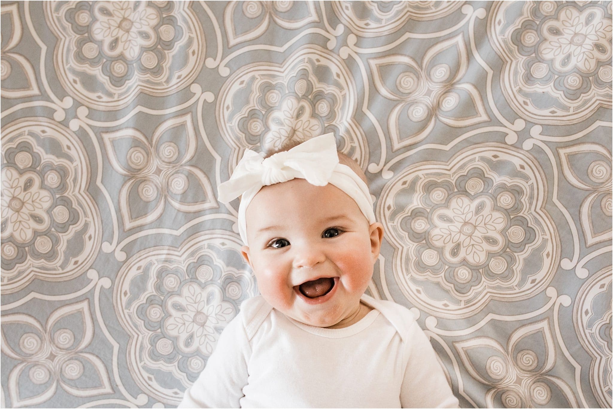 smiling 6 month old baby with white bow