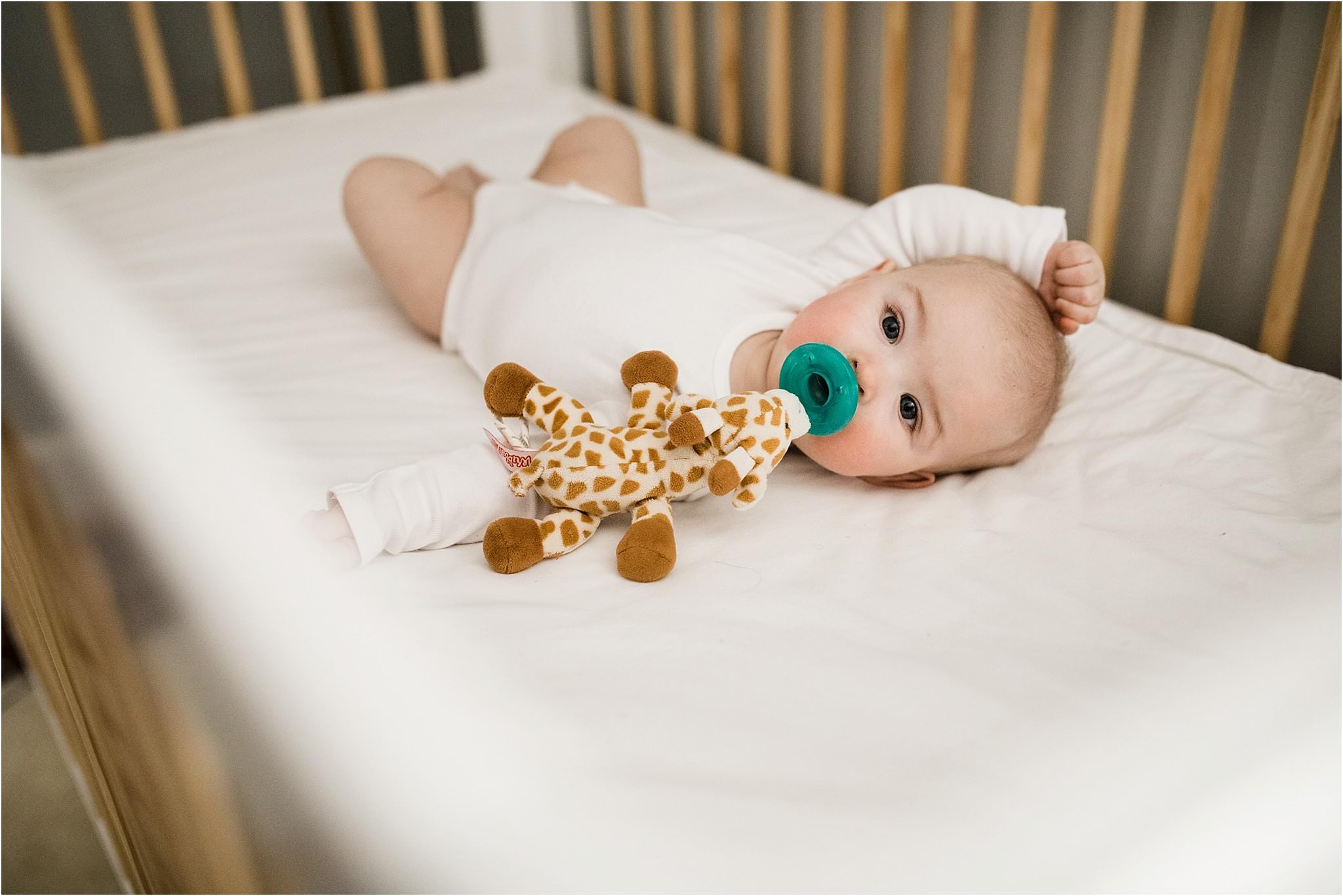 6 month old laying in bed with Wubba