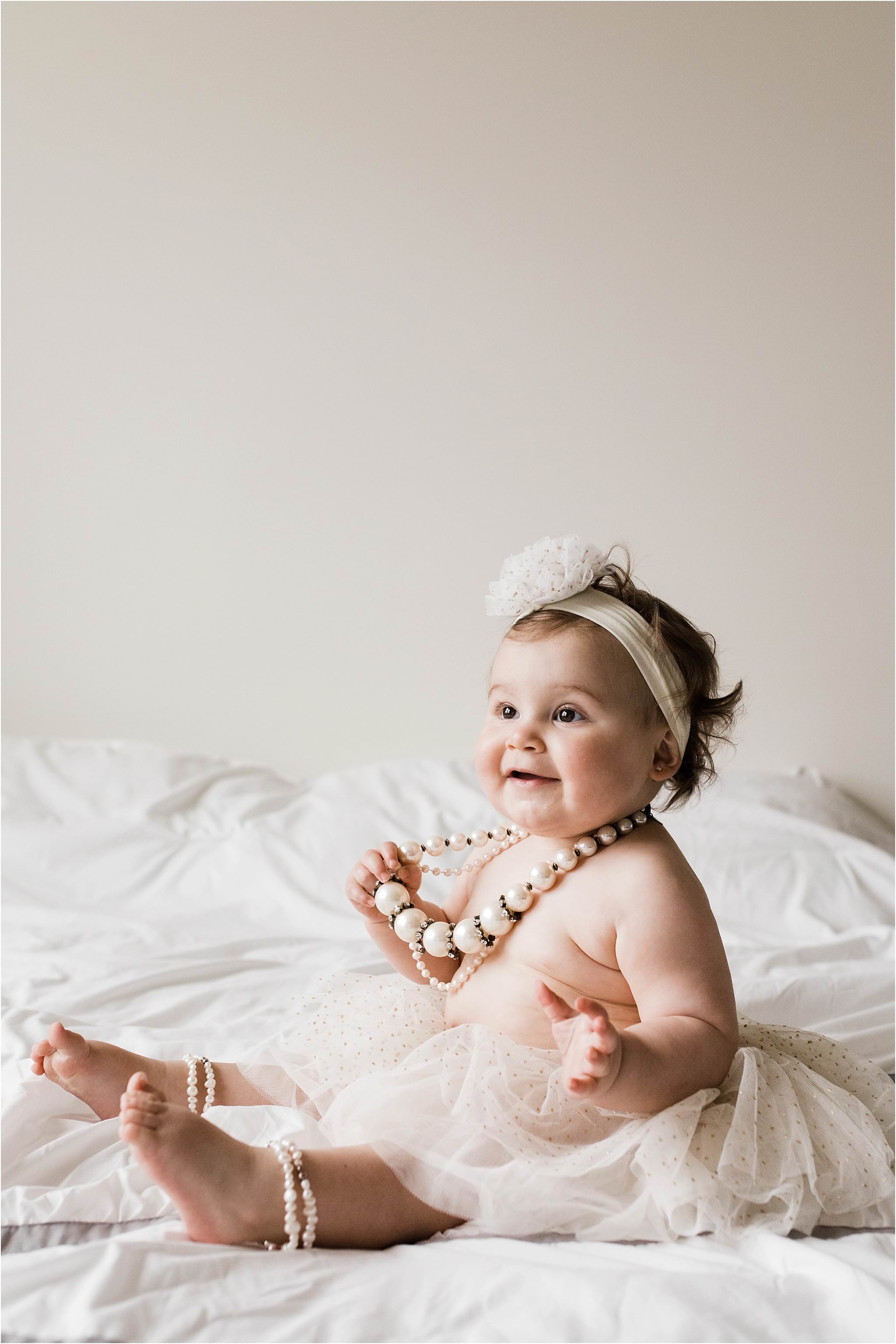 one year old girl wearing grandmothers pearls