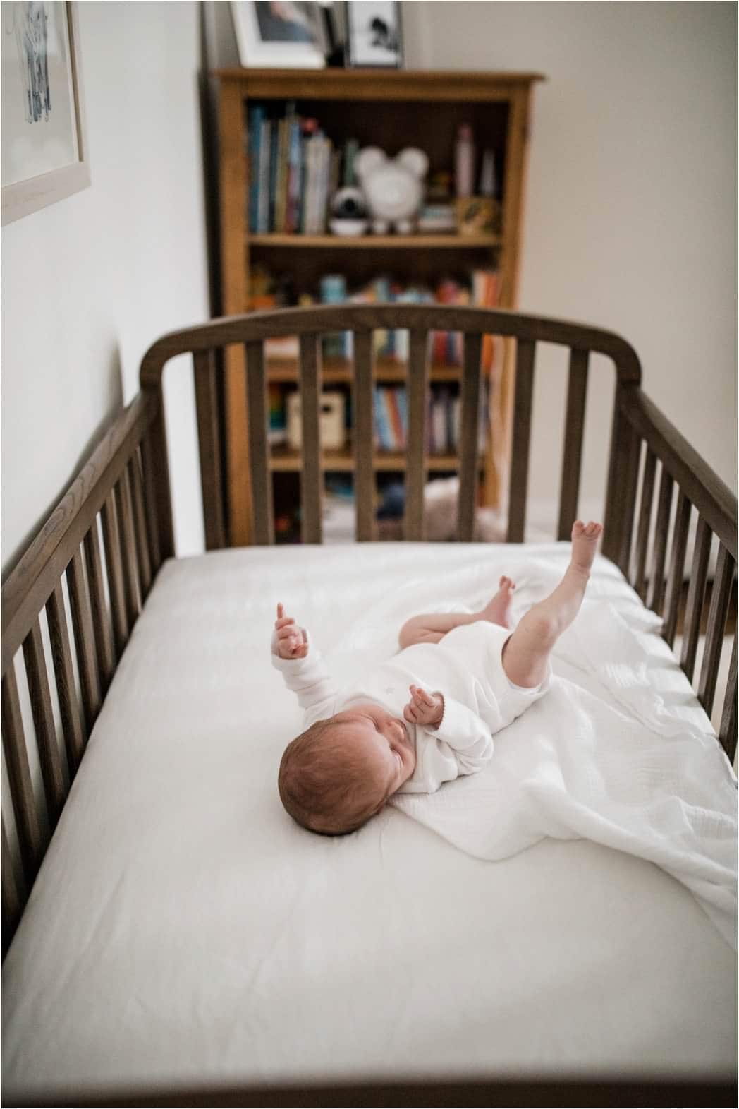 newborn baby stretching in crib