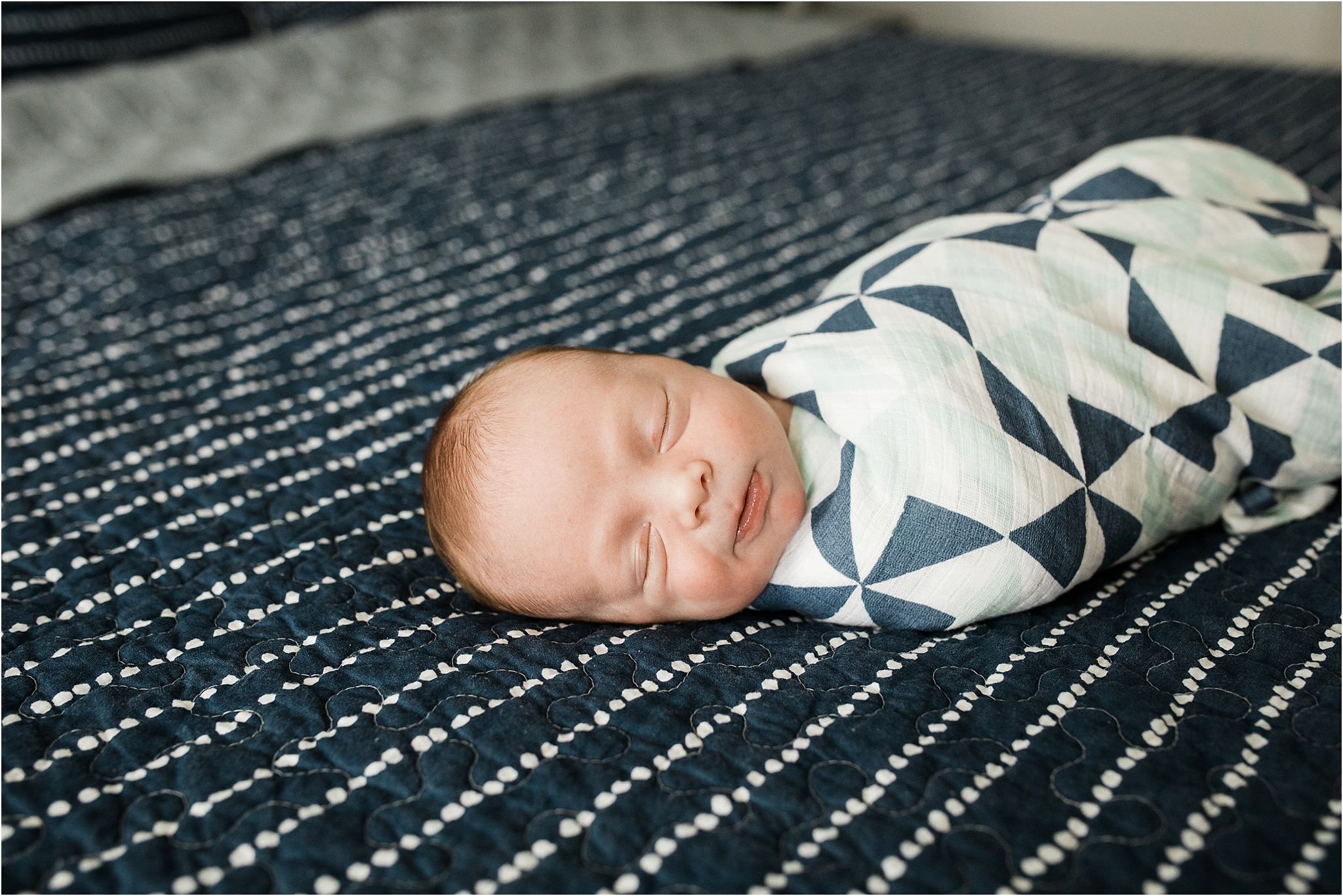 newborn boy in blue pattern swaddle