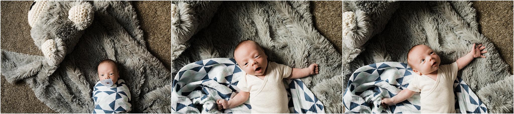 newborn in white onesie stretching on blankets