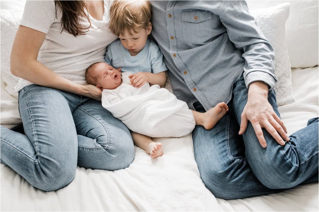 faily snuggled up to swaddled newborn baby 