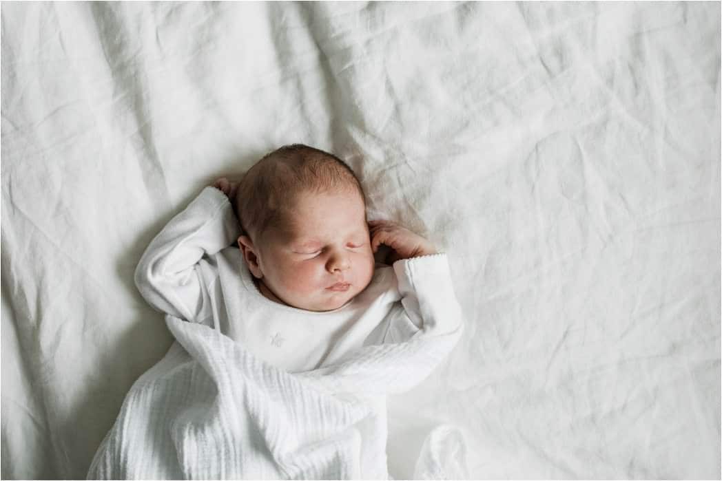 sleepy newborn baby in white onesie