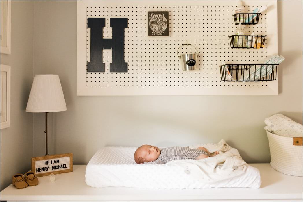 newborn swaddled under pegboard nursery details