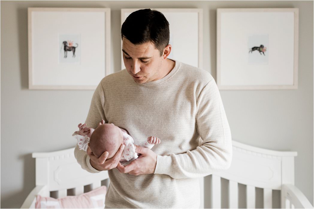 father holding newborn baby girl in nursery