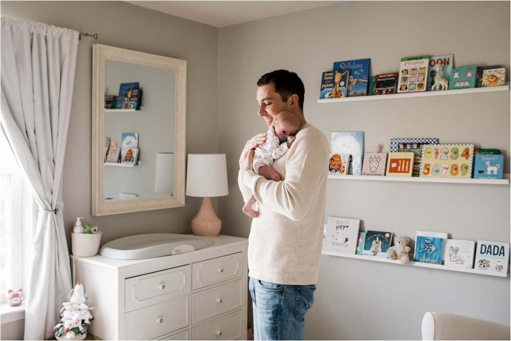 father holding and comforting newborn baby girl in nursery