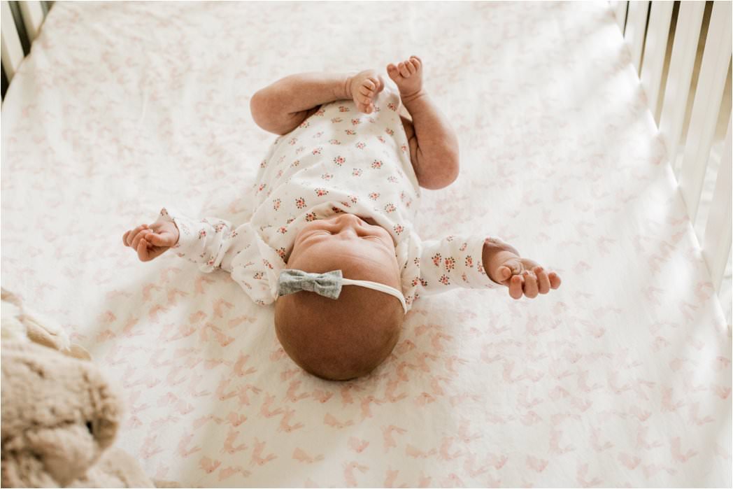 newborn baby girl in floral onesie and bow