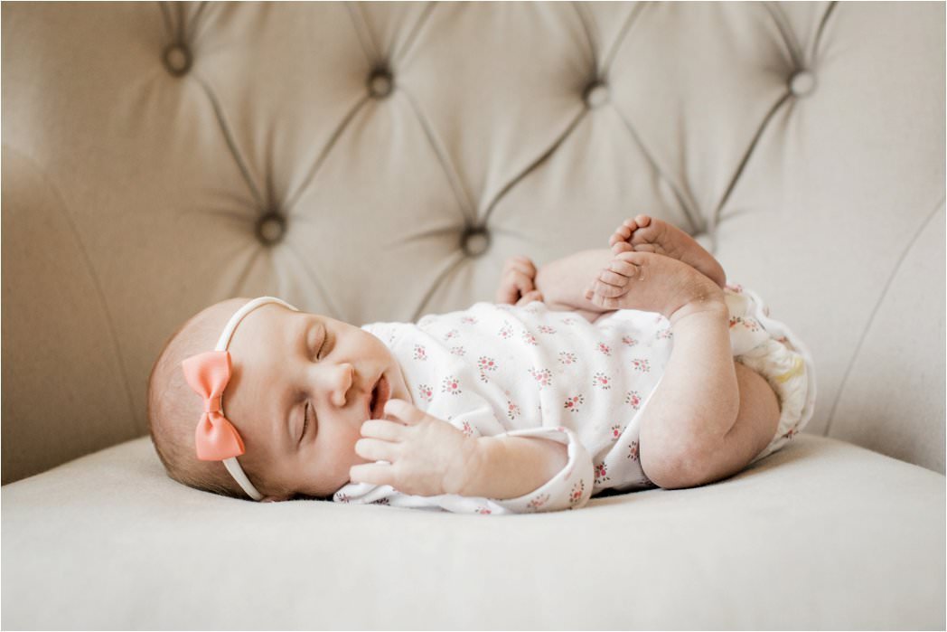 portrait of newborn baby girl in floral onesie and soft pink headband bow