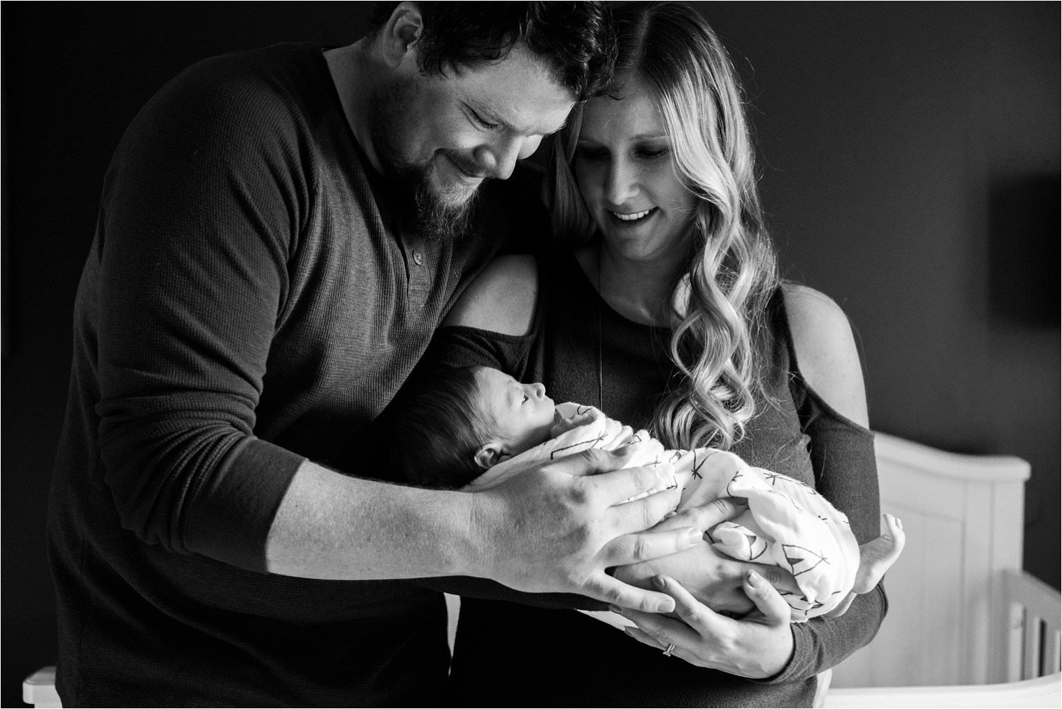 black and white image of new parents holding newborn baby boy