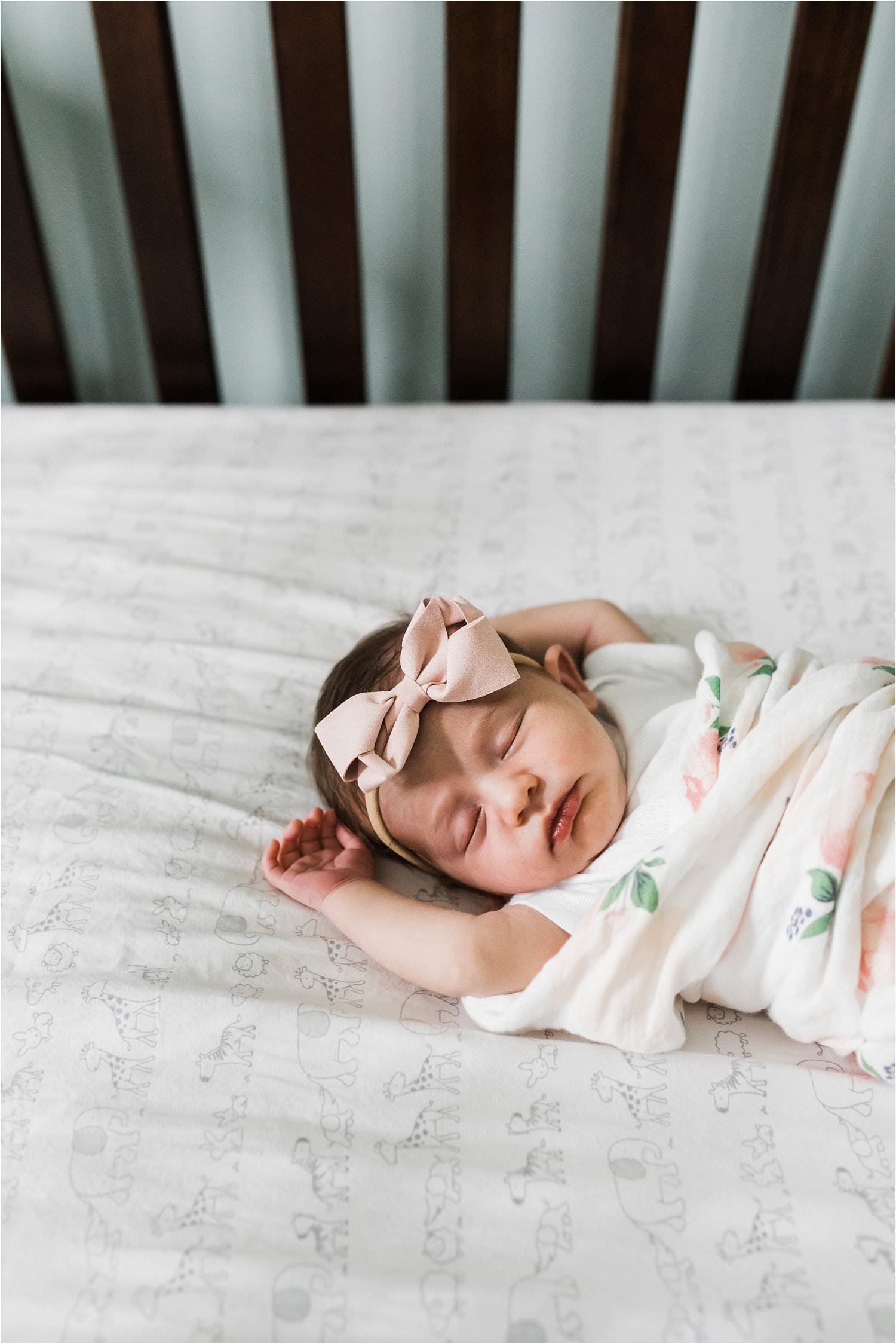 newborn baby sleeping in crib with arms above head