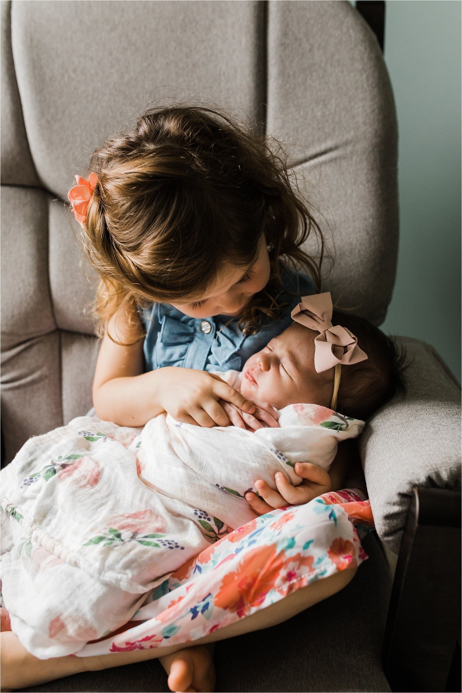 photos of a big sister hold and looking at her new baby sister