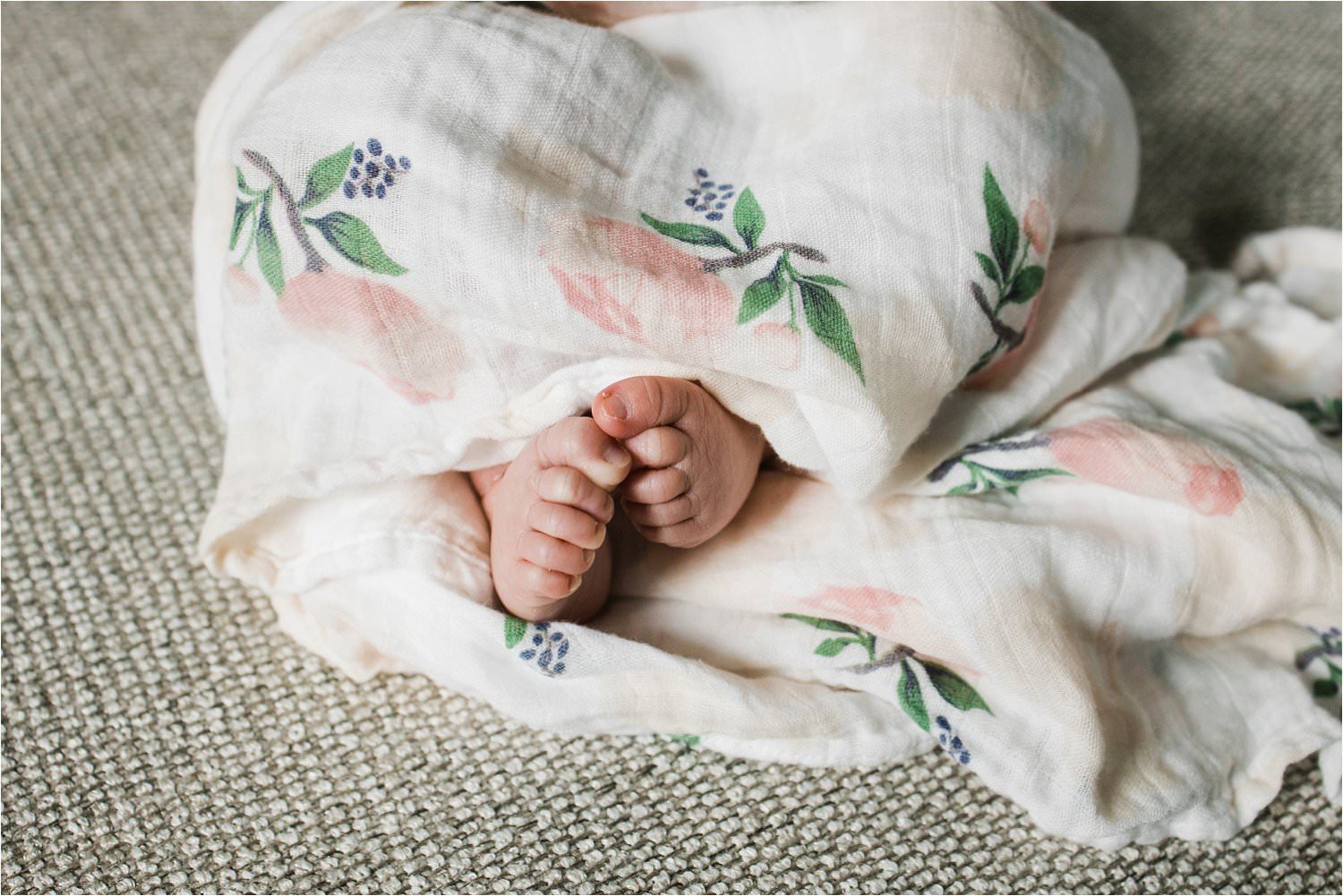 newbron baby toes peeking from a floral swaddle blanket