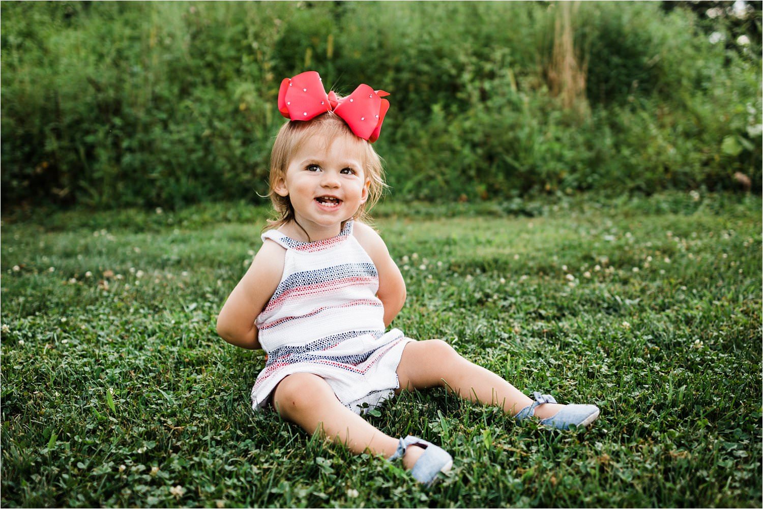 toddler girl in striped romper and pink bow