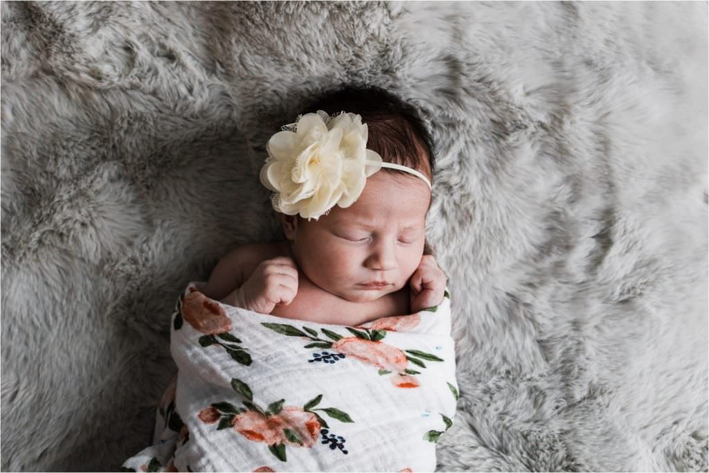 newborn portrait with floral swaddle and flower bow