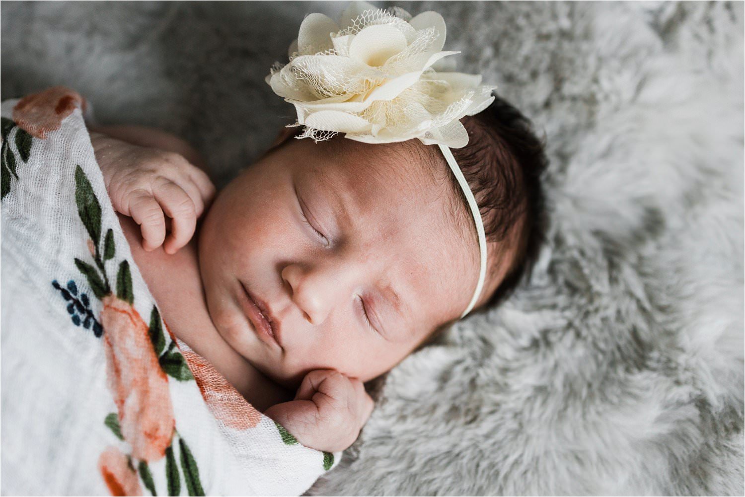 newborn portrait with floral swaddle and flower bow