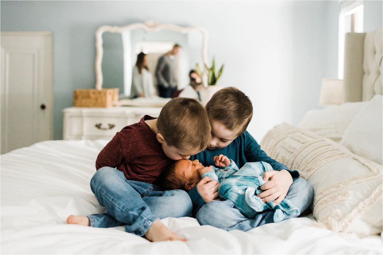 SIBLINGS HOLDING AND KISSING NEWBORN BABY BROTHER