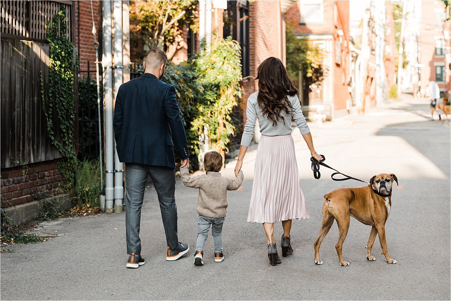 family walking hand in hand with dog